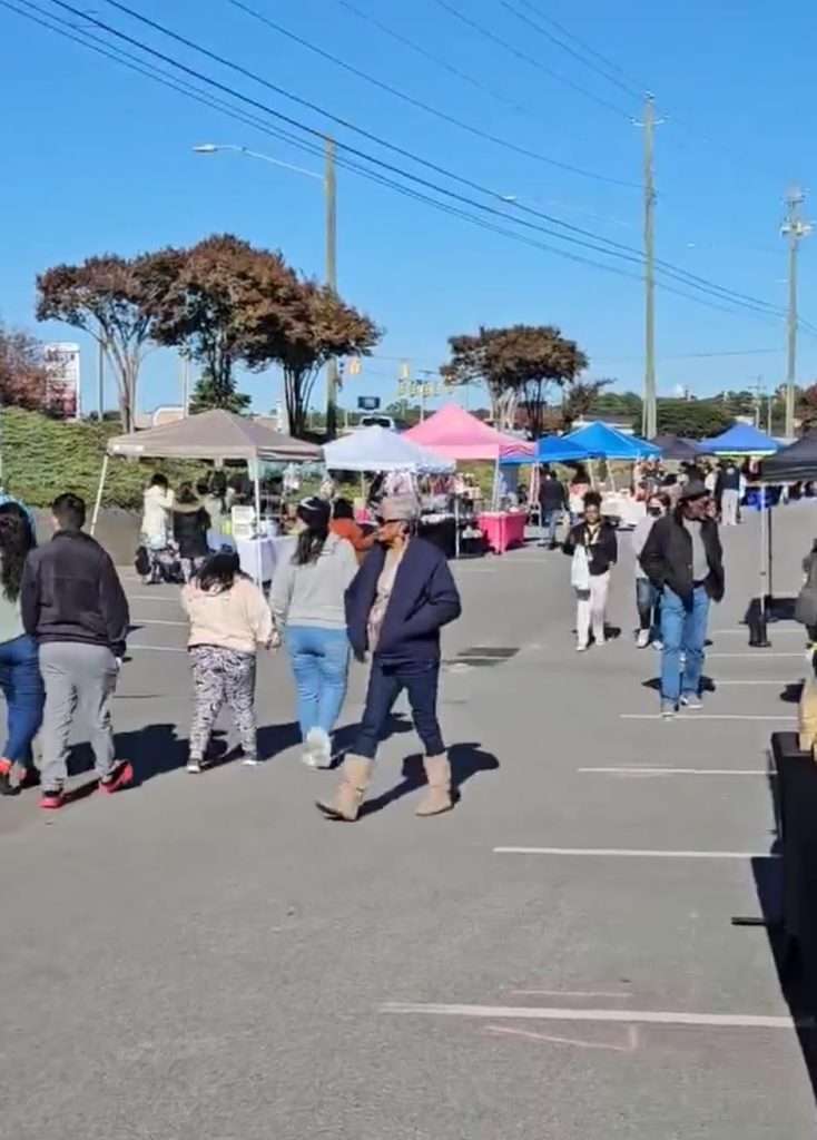 Crowd walking between vendor booths at an outdoor market